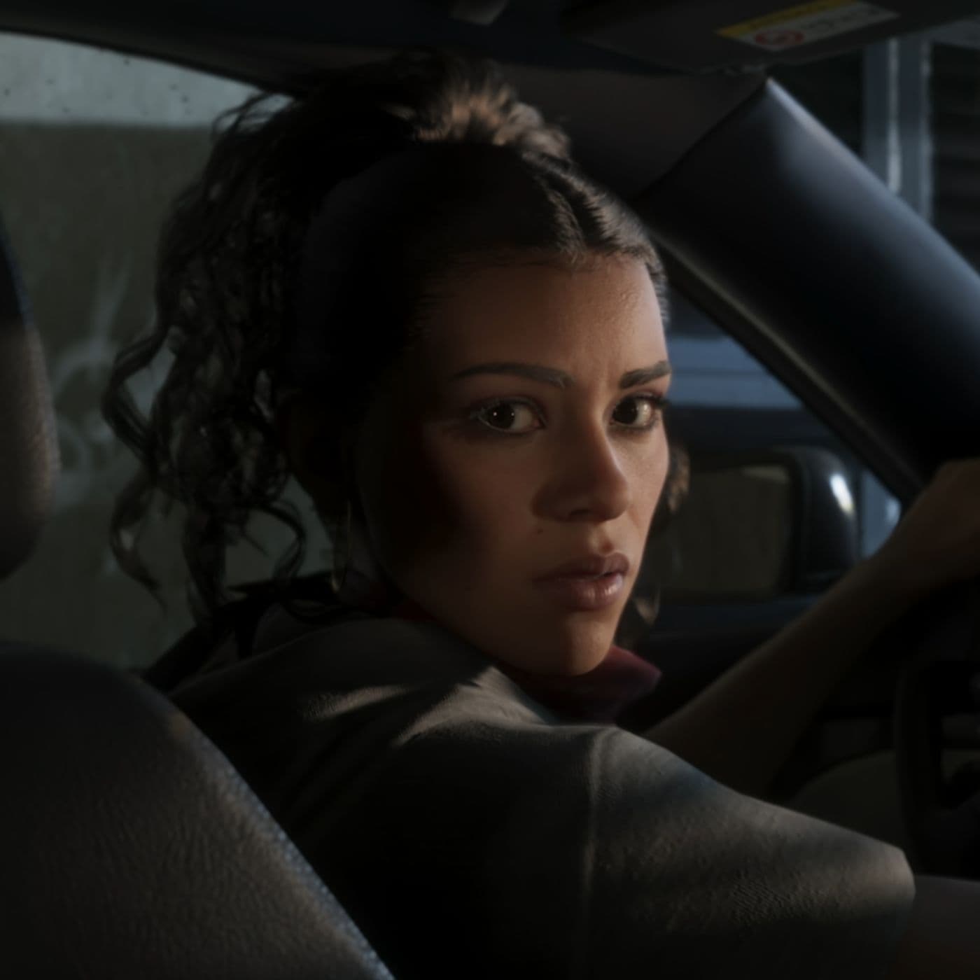 Close-up GTA VI image of Lucia Caminos looking back from the driver seat of a car.